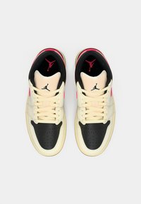 Ζευγάρι κρεμ, μαύρα και ροζ αθλητικά παπούτσια Jordan, με θέα από πάνω, με μαύρα λογότυπα Jumpman στις γλώσσες και στις εσωτερικές σόλες.