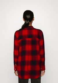 Chemise à carreaux rouge et noir à boutons, coupe décontractée, manches longues et détail d'empiècement au dos, fabriquée dans un tissu doux et texturé.