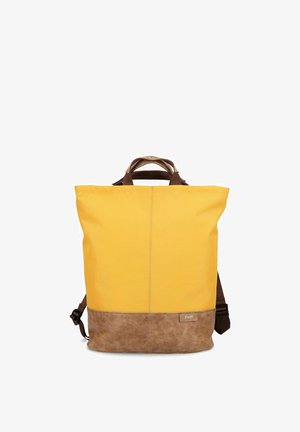 Sac à dos jaune avec un fond et des poignées en cuir marron, équipé de bretelles réglables et d'une petite étiquette de logo à l'avant.