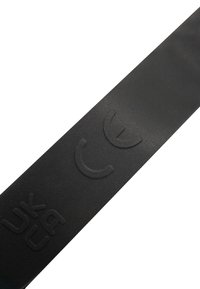 Superficie negra texturizada con marca de certificación UKCA en letras en relieve.