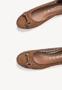 Chaussures plates marron en cuir tressé avec bouts arrondis et bride en cuir décorative avec boucle métallique sur le dessus.