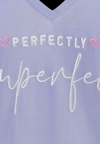 Lavendel V-halsstof met geborduurde tekst "PERFECTLY imperfect" in het wit, geflankeerd door twee kleine roze hartjes.