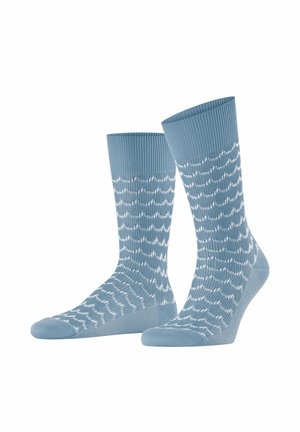 Coppia di calzini blu al polpaccio con motivi a zigzag ondulati bianchi, polsini a coste e aree della suola testurizzate su sfondo bianco.
