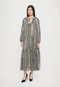 Lang, lagdelt kjole laget av lett stoff med sort og beige slangeskrift. Volang halslinning og lange ermer med knappdetaljer.