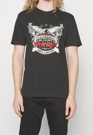 Black cotton t-shirt featuring a central graphic with eagles, stars, and the "Wrangler" logo in red and white, with a classic crew neckline.