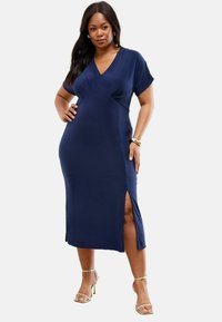 Robe bleu marine, longueur genou, en tissu lisse. Décolleté en V avec des manches courtes et détail de fente sur le côté. Design simple avec une silhouette ajustée.