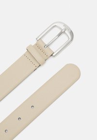 Cinto de pele bege com fivela de metal prateada. Apresenta um acabamento texturizado, bordas limpas e vários furos para ajustamento.