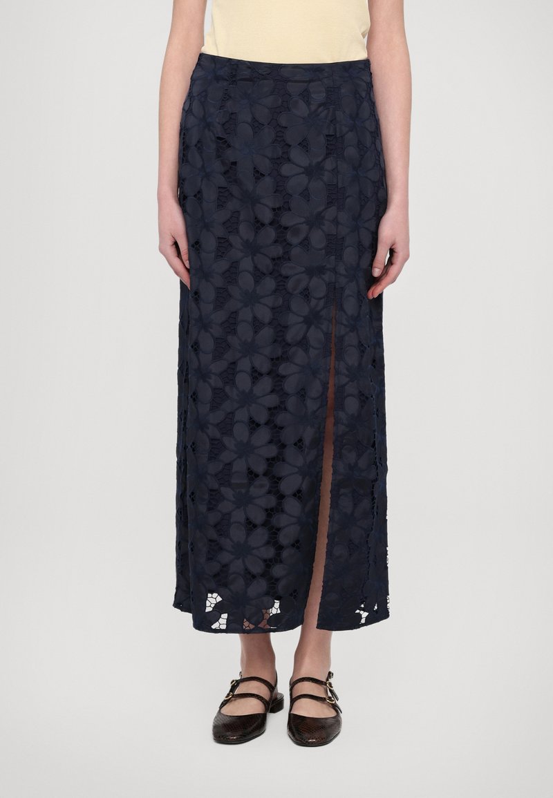 Mørkeblå blonde maxi skjørt med blomsterprint, med en sideliv. Laget tekstur gir dybde, stilt med flate brune sko.