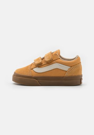 Zapatillas de ante marrón con dos correas de Velcro, suela de goma y franja lateral color crema. Diseño de perfil bajo con forro interior suave.