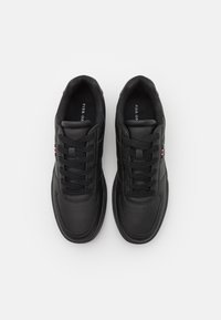 Black sneakers with a smooth leather upper, round toe, flat laces, and a small red and white logo on the side, set against a white background.