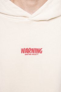 Cremfarbene Kapuzenjacke mit rotem Aufdruck der Worte "WARNING KAOTIKO SOCIETY" auf der Brust. Weicher Stoff mit lässigem Schnitt und verstellbarer Kapuze.