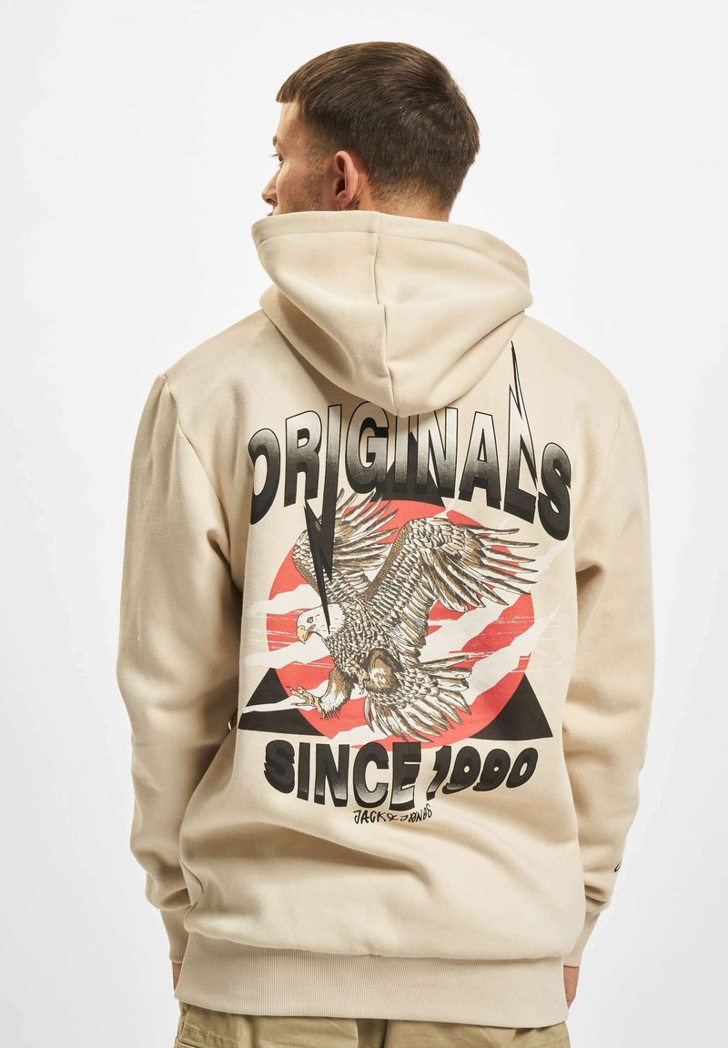 Bež dukserica s grafičkim printom orla i natpisom "ORIGINALS SINCE 1990" na leđima, s kontrastnim crnim i crvenim elementima.