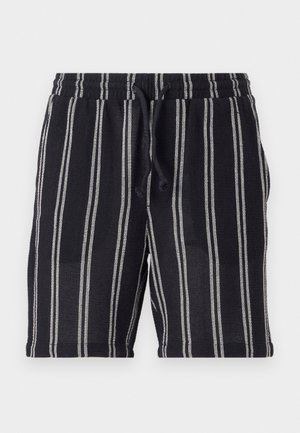 Pantaloni scurți cu dungi alb-negru, cu talie elastică, închidere cu șnur și un material texturat. Au o lungime până la jumătatea coapsei.