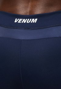 Κοντινό πλάνο της κάτω πλάτης ενός ατόμου που φοράει αθλητική ενδυμασία Venum σε ναυτικό μπλε με ορατές ραφές και λογότυπο στη ζώνη της μέσης.