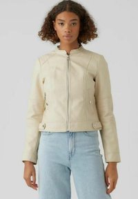 Giacca in pelle beige con una forma aderente, chiusura con zip e tasche laterali. Presenta dettagli delle cuciture sulle spalle e sui polsini.