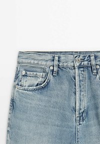 Jeans in denim azzurro chiaro con vita alta, dotati di una tasca frontale, molteplici passanti per la cintura e hardware argentato sul bottone di chiusura.