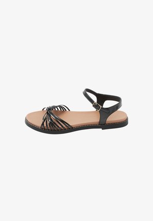 Sandalo piatto nero con sottili cinturini incrociati sulle dita, cinturino alla caviglia con fibbia, soletta color cuoio e suola nera.