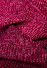 Strickstoff in einem leuchtenden Magenta, mit einem strukturierten Rippmuster unterschiedlicher Dicke und einem weichen, gemütlichen Aussehen.