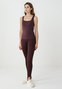 Top con scollatura quadrata di color bordeaux abbinato a leggings coordinati. Tessuto morbido e elastico. Sneakers bianche completano l'outfit.