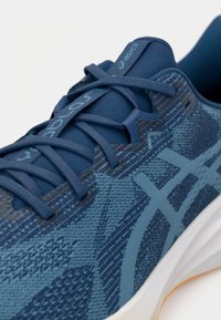 Scarpa sportiva blu con tomaia in maglia testurizzata, lacci tonali e accenti azzurri a contrasto. Presenta una suola bianca imbottita.