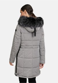 Manteau doudoune gris avec capuche en fausse fourrure, texture matelassée, ceinture ajustable et poches latérales. Il présente une bande d'accent noire à l'arrière.