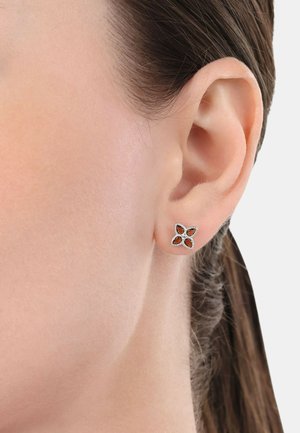 Silberne Steckerohrringe im Blumendesign, mit vier Blütenblattformen, von denen jede ein ausgeschnittenes Zentrum hat und mit kleinen weißen Strasssteinen verziert ist.