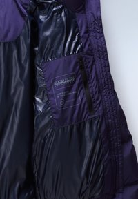 Wnętrze fioletowej kurtki puchowej, z gładkim, błyszczącym materiałem, kieszenią na zamek oraz metką wskazującą, że jest w 100% wolna od puchu i wykonana z Thermo-Fiber.