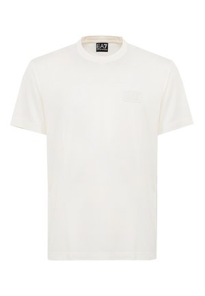Camiseta blanca de manga corta con cuello redondo y logotipo en relieve sutil en el pecho, además de etiqueta EA7 Emporio Armani en el interior del cuello.