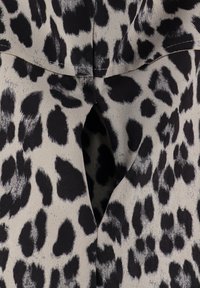 Panterprint stof in zwart en grijs, met een gestructureerd oppervlak en een sleutelgat uitsnijding bij de halslijn.