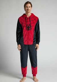 Pijama de una pieza de forro polar en rojo y azul marino con diseño de araña, capucha y cremallera frontal. Los puños y el dobladillo son acanalados para mayor comodidad.