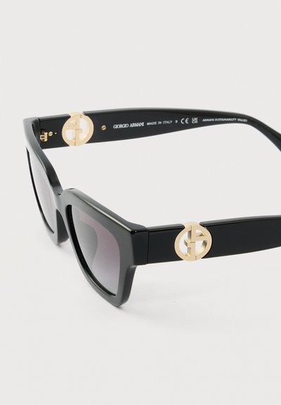 Μαύρα ορθογώνια γυαλιά ηλίου με σκουρόχρωμους φακούς, χρυσό λογότυπο Giorgio Armani στα κέρατα και κείμενο "Made in Italy" στο εσωτερικό του μπράτσου του σκελετού.