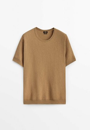 Sweter dzianinowy z krótkim rękawem w kolorze kamelowym, o okrągłym dekolcie i ściągaczach przy rękawach, ułożony płasko na białym tle.