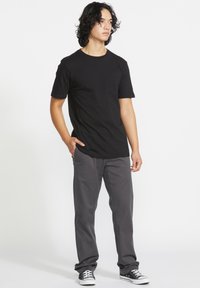 Black short-sleeve t-shirt with a chest pocket, paired with gray straight-leg pants and black sneakers. Smooth fabric and classic fit.