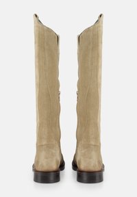 Beige Wildleder-Stiefel bis zum Knie mit leicht geschwungenem Oberteil, ausgestattet mit silbernen Reißverschlüssen an den Seiten und einem dunkelbraunen Blockabsatz.