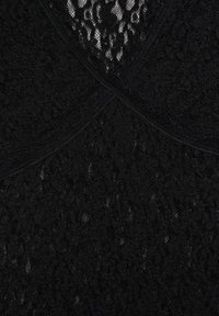 Schwarzer Spitzenstoff mit Blumenmustern und überlappenden Abschnitten, die in der Mitte ein gekreuztes Detail bilden.