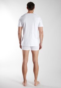 White cotton t-shirt with short sleeves and a round neck, paired with white boxer shorts, viewed from the back. Smooth texture and simple design.