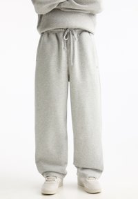 Graue Sweatpants aus einem weichen Baumwollmix, mit einem elastischen Bund und einer Kordel, weit geschnittenen Beinen und seitlichen Taschen.