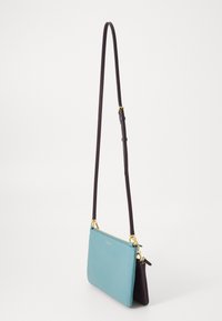 Dvítonis odinis per petį nešiojamas krepšys su turkio spalvos priekiu, tamsiai violetiniu užnugariu, auksinėmis detalėmis ir reguliuojamu tamsiai violetiniu diržu.