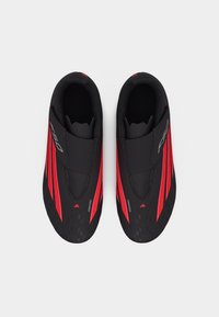 Ζεύγος μαύρων και κόκκινων αθλητικών παπουτσιών ποδηλασίας με αεροδυναμικό σχεδιασμό και ελαστικές κλειδαριές με λουράκια, εμφανιζόμενα από πάνω σε λευκό φόντο.