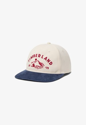 Gorra beige de Timberland con visera de pana azul marino, con logotipo de montaña bordado en rojo y texto "TIMBERLAND EST '73" en la parte delantera.