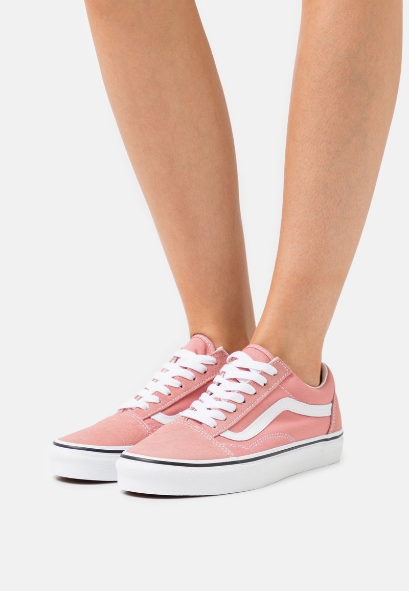 Baskets en toile rose avec des lacets blancs, des rayures latérales blanches et une semelle en caoutchouc avec une ligne accent noire le long du bord.