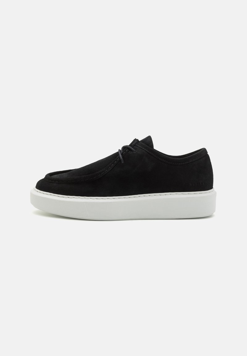 Black suede sneaker with a rounded toe, white rubber sole, and minimalist design. Features subtle stitching and a low-profile lace system.