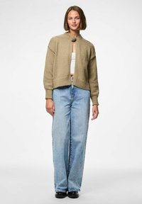 Knit, beige cropped cardigan with a round collar and a front closure, paired with light blue high-waisted wide-leg jeans and black shoes.