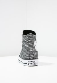 Sneaker alta Converse All Star in bianco e nero con un motivo a diamante testurizzato, dotata di un'etichetta logo bianca e branding sulla suola nera.
