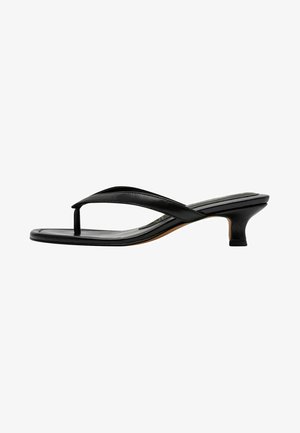 Tonguelette noire avec une fine lanière, bout pointu et talon kitten de 3,8 cm. Texture lisse avec une finition brillante.