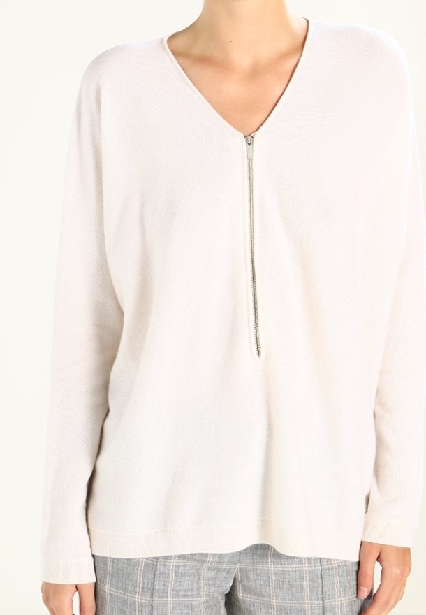 Ljusbeige tröja, V-ringning, helärmade, dragkedja framtill, mjuk textur, avslappnad passform, passar bra med grå rutiga byxor.