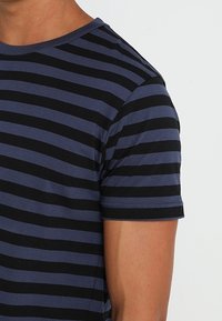 Camiseta de manga corta con rayas horizontales en azul marino y negro, confeccionada en una tela suave con cuello redondo y un corte regular.