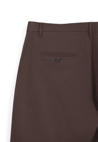 Pantalon en tissu marron sur un fond blanc, montrant une poche arrière avec bouton et passants de ceinture.