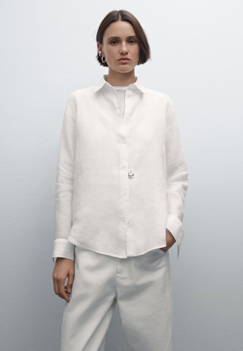 Witte linnen overhemd met knopen, kraag, lange mouwen en een losse pasvorm, gecombineerd met bijpassende witte broek. Eenvoudig ontwerp met een zachte textuur.