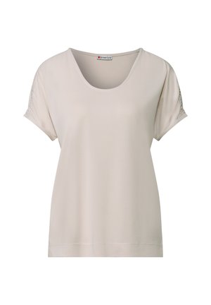 Licht beige kort mouwtop met een ronde halslijn, zachte textuur en geplooide details op de mouwen. Ontspannen pasvorm met een rechte onderzoom.
